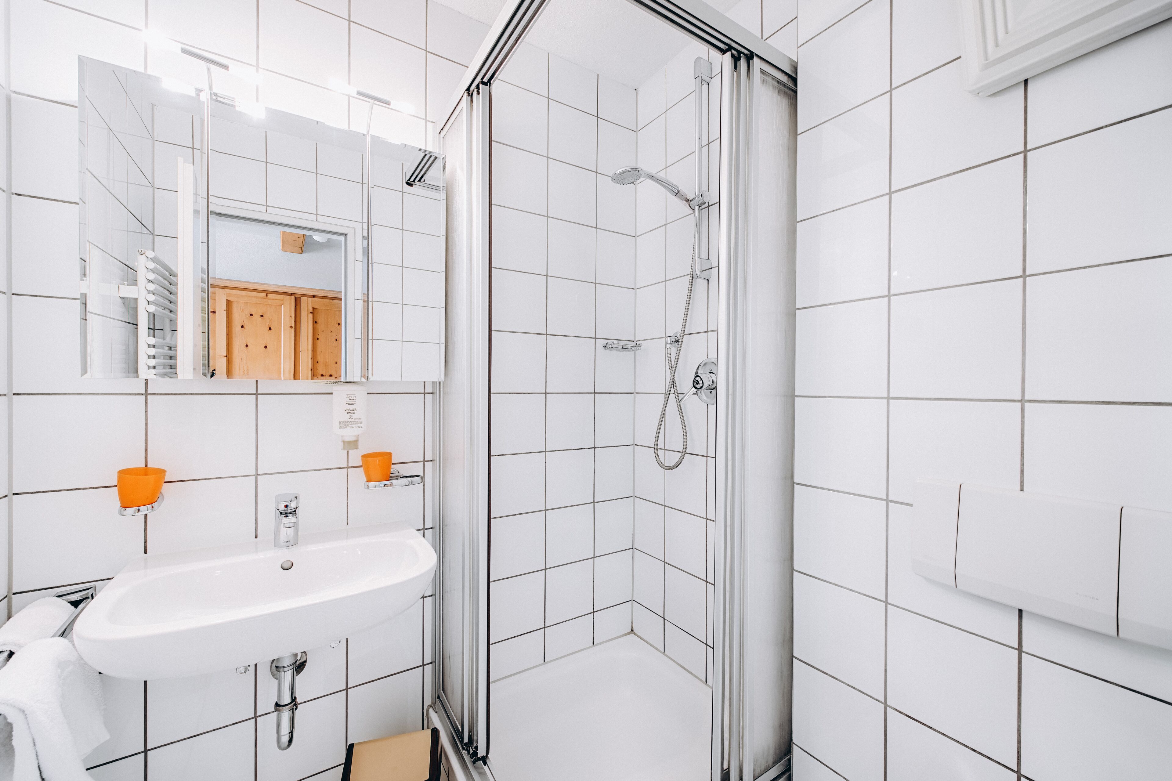 A modern bathroom with a white sink, mirror, and shower.