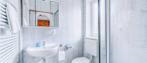 A bathroom with a white sink, toilet, and a mirror above the sink.