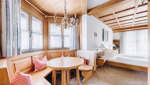 Una habitación acogedora con un banco de madera, una mesa redonda y una cama.