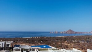 Vista costera con cielo despejado, piscina y un litoral rocoso distante.