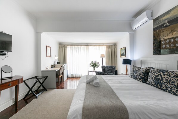 Una habitación de hotel con una cama, un escritorio, una silla, un televisor y aire acondicionado.