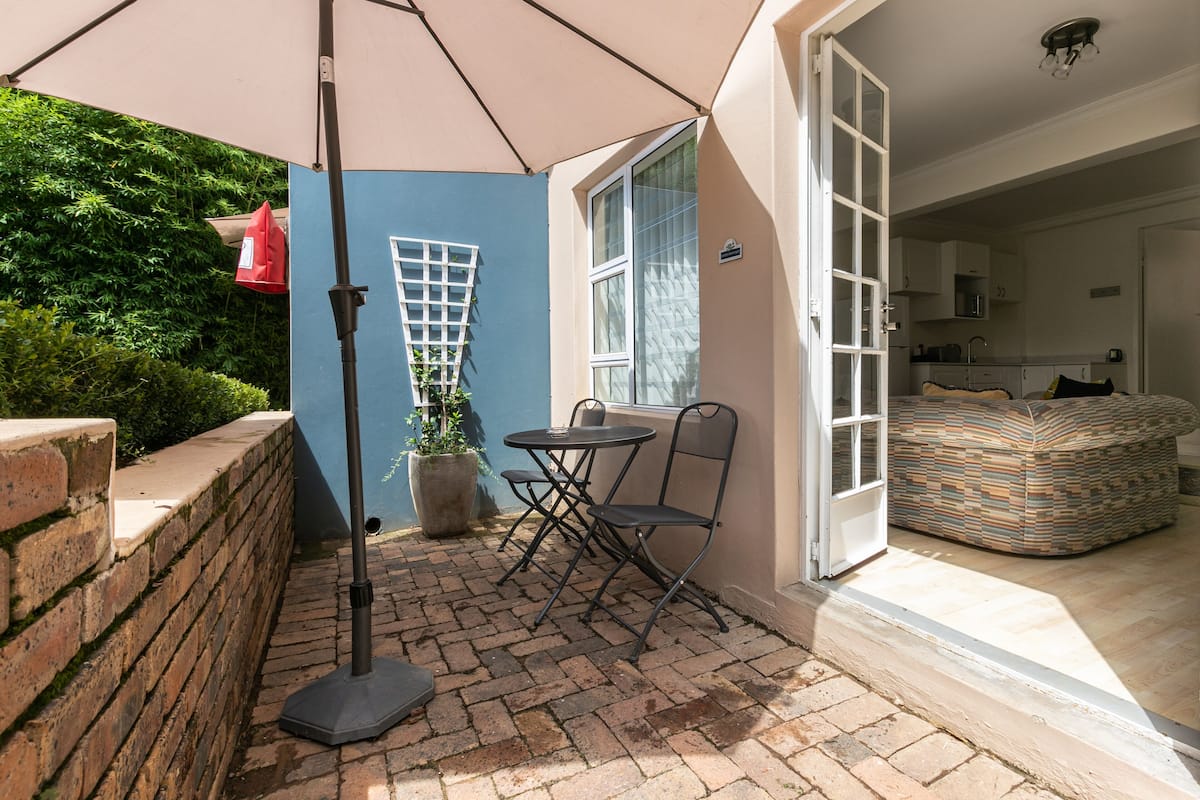A patio with a table and chairs, a potted plant, and a red bag hanging on a wall.