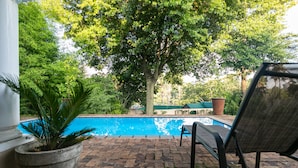 A pool area with a brick patio, a lounge chair, and a large tree providing shade. - Emmarentia Guest house  (Randburg)