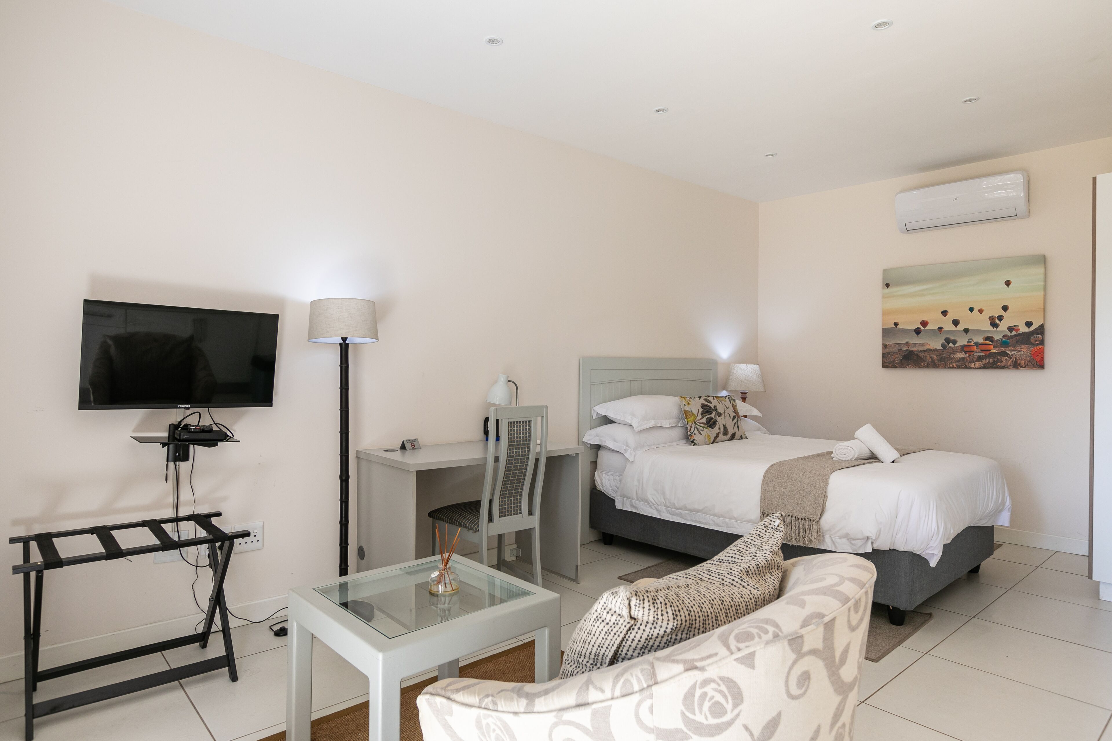 A hotel room with a bed, a desk, a TV, a chair, and a couch.