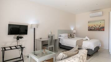 A hotel room with a bed, a desk, a TV, a chair, and a couch.