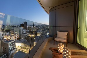 A modern balcony with a city view, a cushioned chair, and decorative wooden stools. - Saffron Suite | Retreat with Skyline Views & Pool (Nicosia)