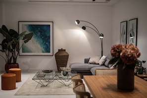 A modern living room with a sofa, coffee table, and a large abstract painting. - Saffron Suite | Retreat with Skyline Views & Pool (Nicosia)