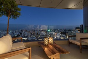 A balcony with a city view, a wooden table, and two white chairs. - Saffron Suite | Retreat with Skyline Views & Pool (Nicosia)