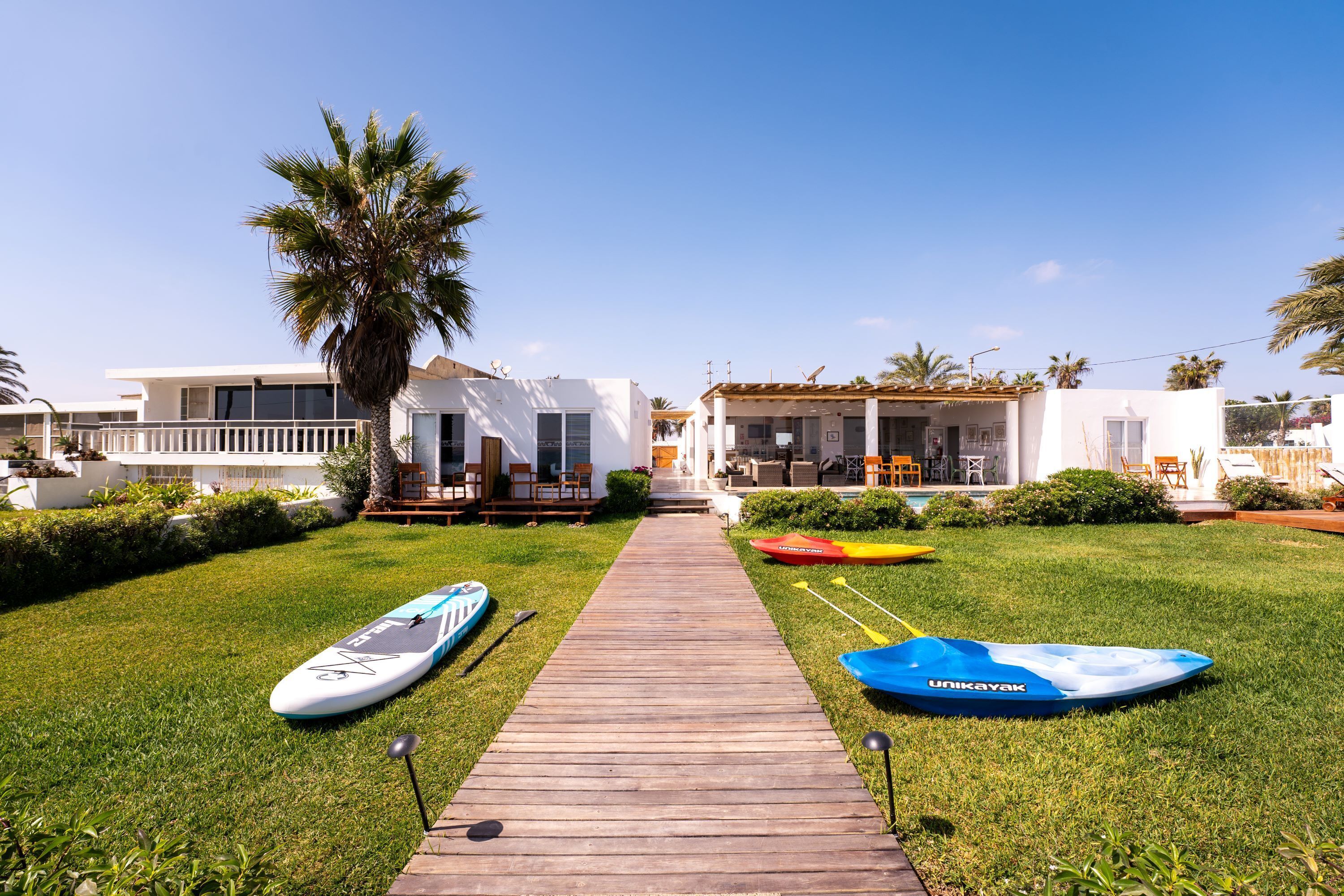 A pathway leading to a white building with a covered patio area.