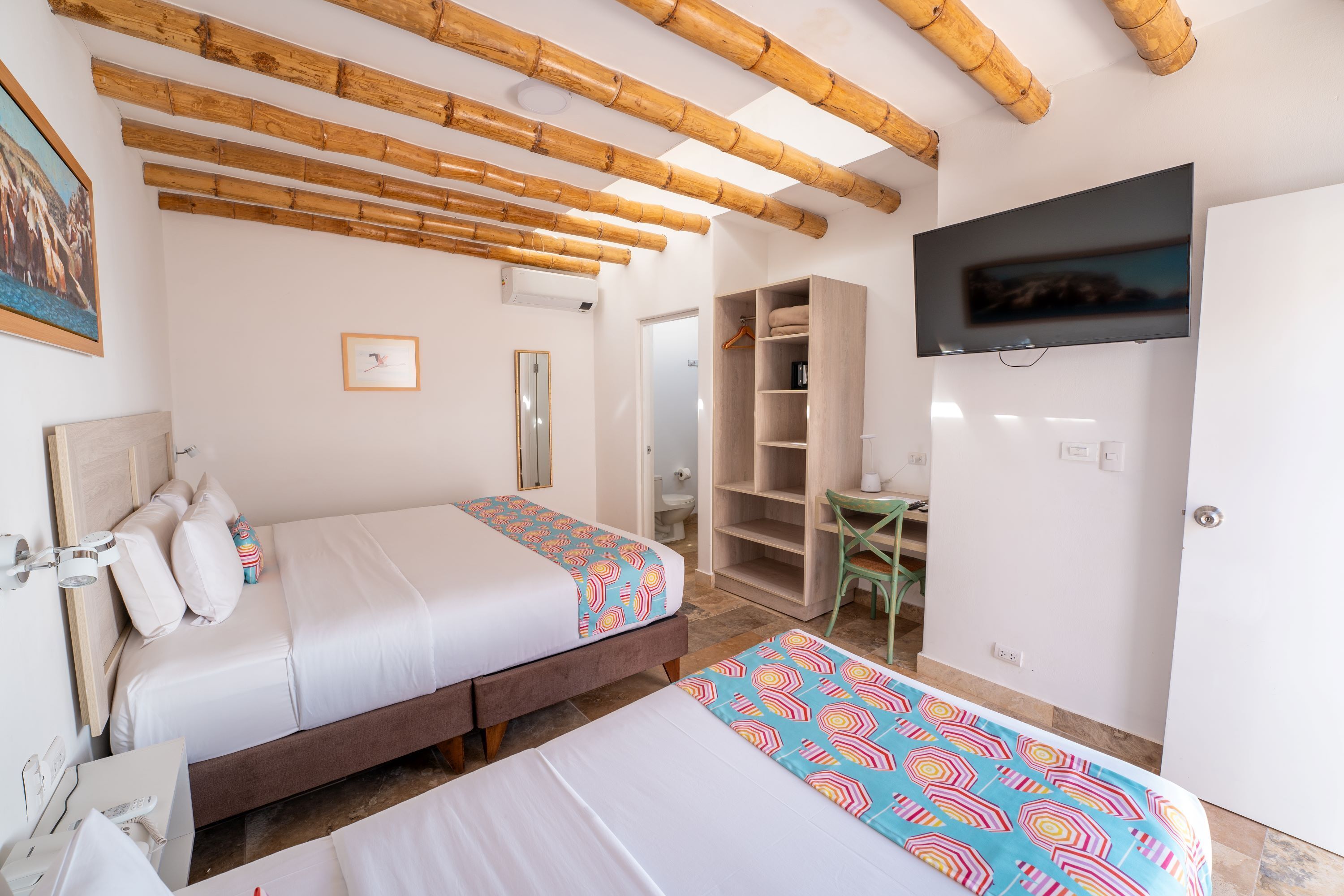 A hotel room with two beds, a TV, a wardrobe, and a desk.