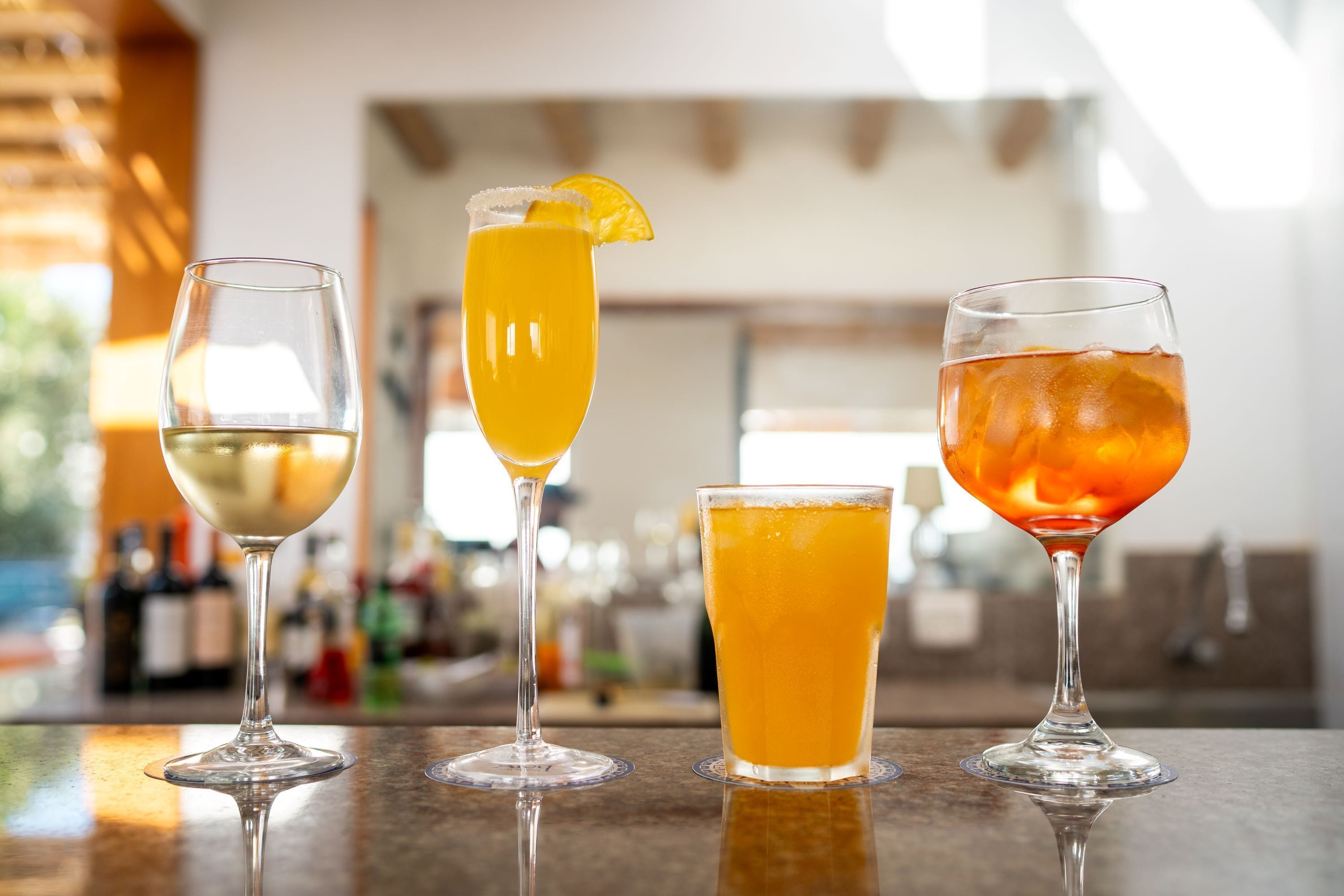Three glasses of different beverages on a bar counter.