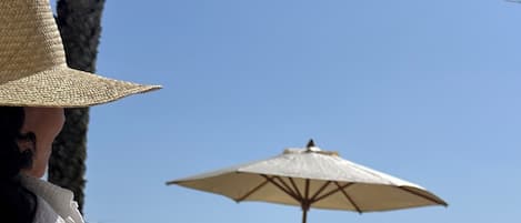 A person relaxing on a lounge chair with a view of the sea and mountains.