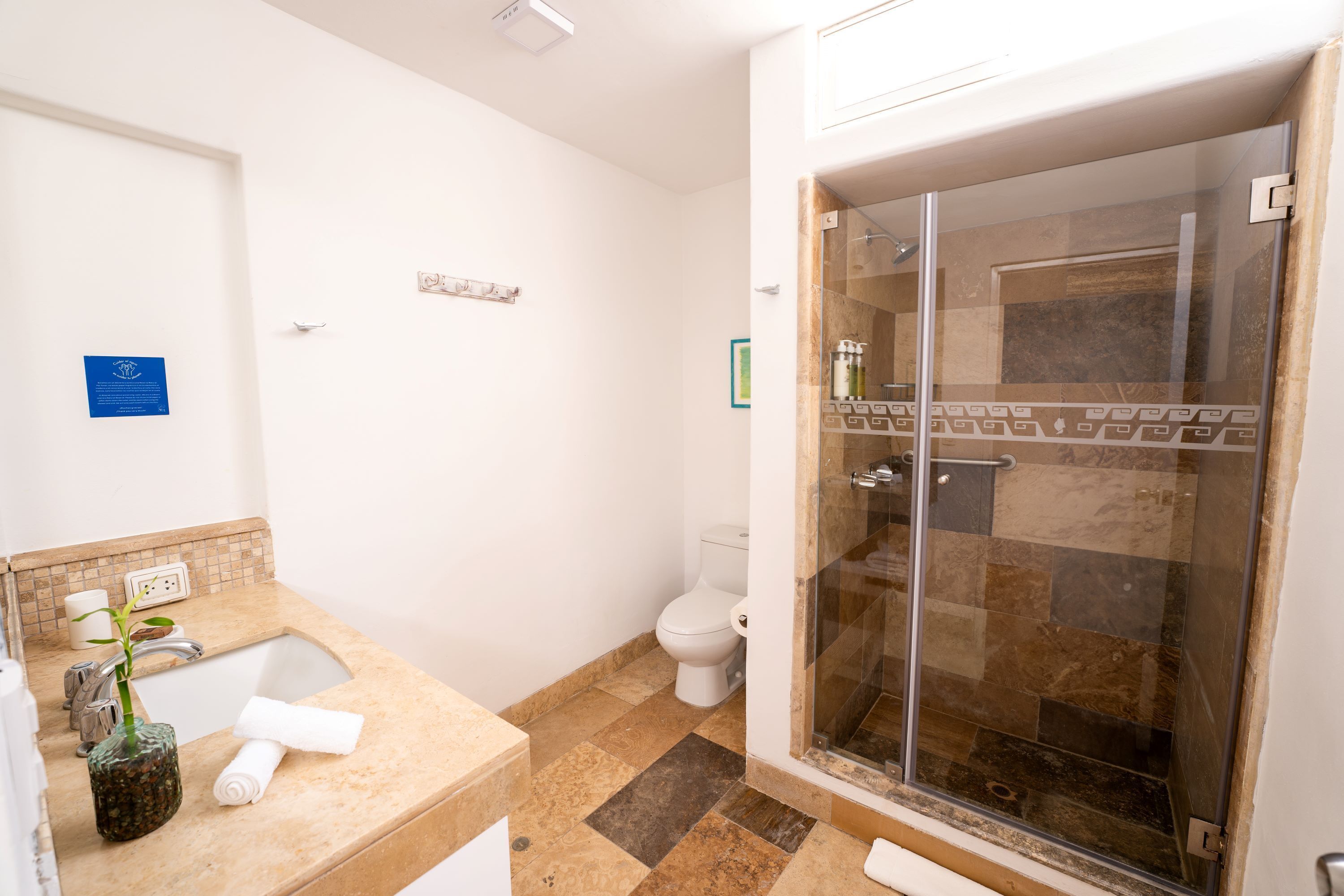 A bathroom with a sink, toilet, and glass-enclosed shower.