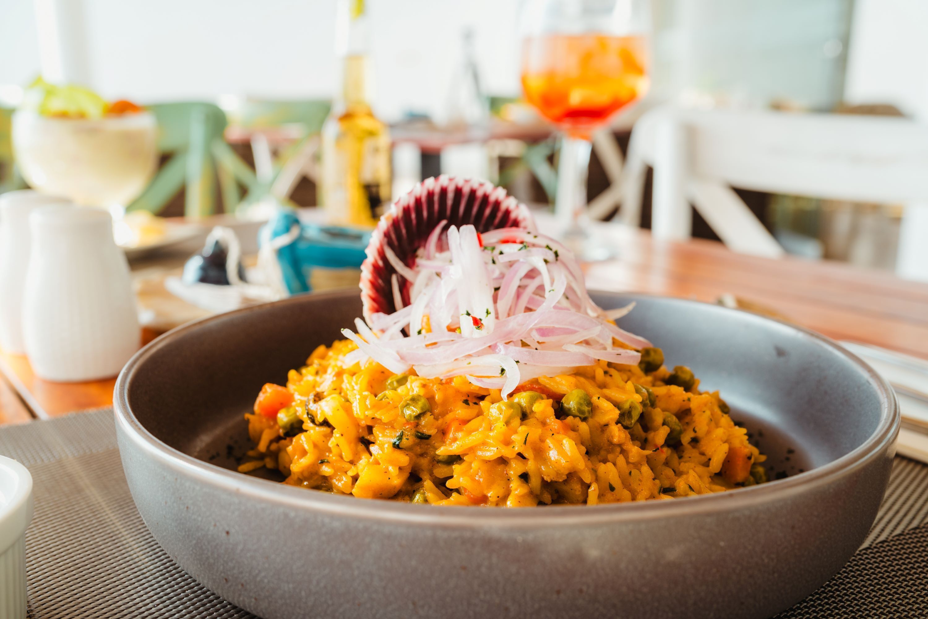 Un tazón de arroz con vegetales y una concha decorativa encima.