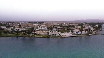 Vista aérea de una zona residencial costera con casas, un puerto deportivo y una playa.