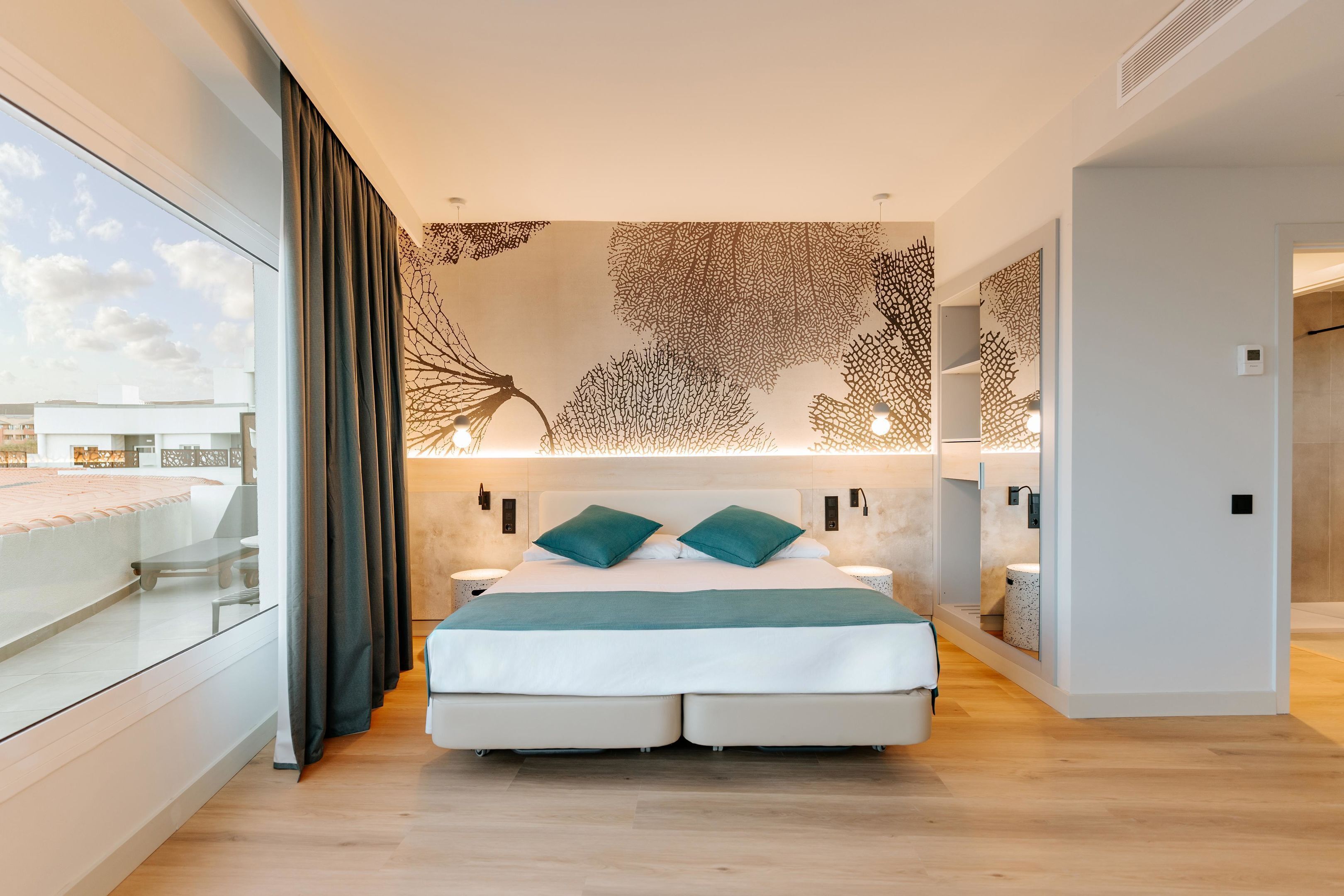Une chambre moderne avec un grand lit, un balcon en verre et un mur décoratif.
