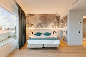 A modern bedroom with a large bed, a glass balcony, and a decorative wall.