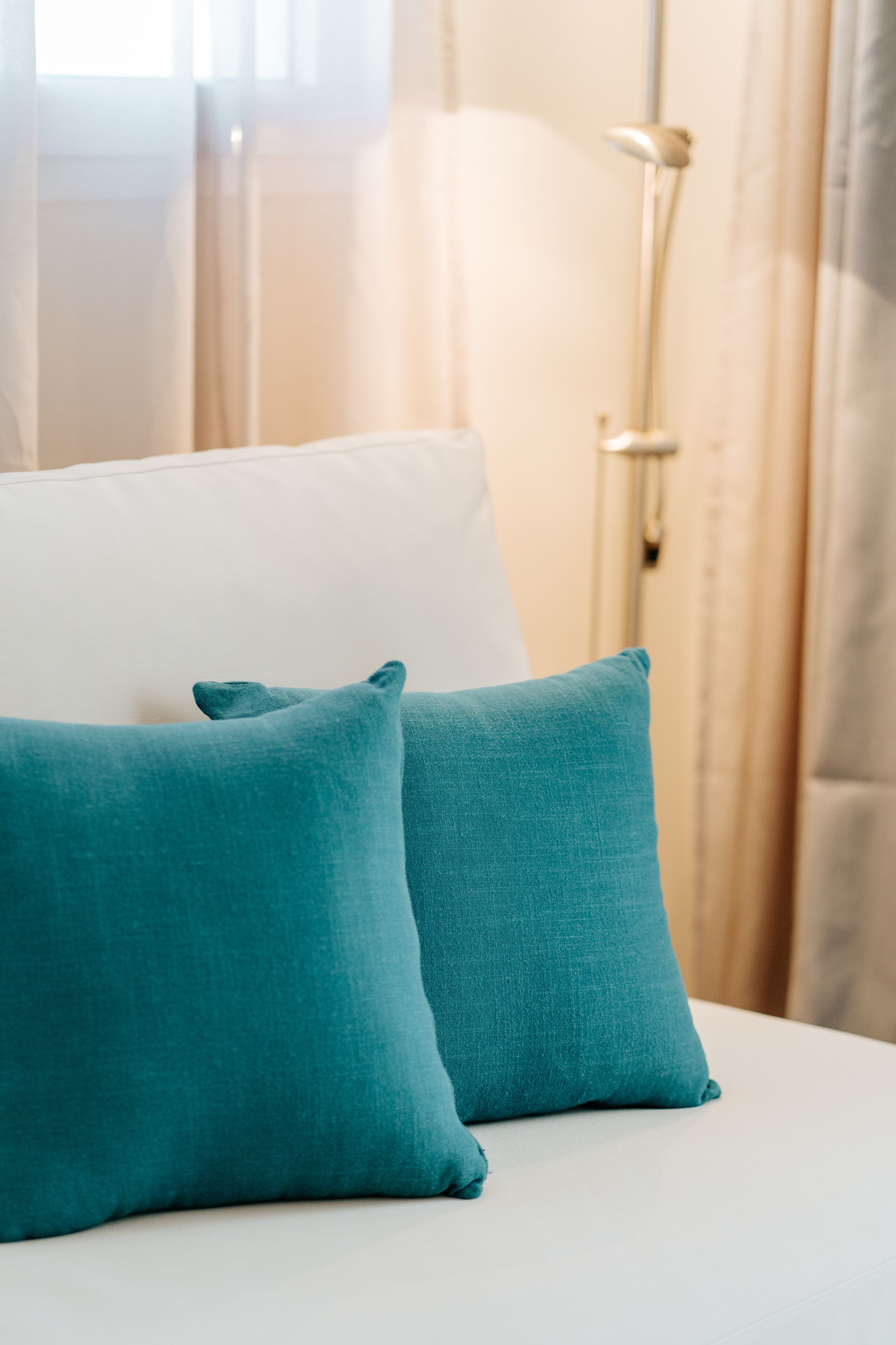 A bed with two teal pillows and a white headboard.