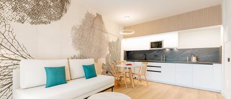 A modern kitchen with white cabinets, a black countertop, and a wooden dining table.