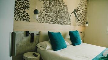 A bed with teal pillows, a white bedspread, and a wall art piece above it.