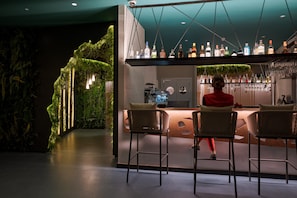 A bar area with a green wall, bar stools, and a variety of bottles. - 001 HIGOS BEACH BOUTIQUE Singular Hotel Residence (Pajara)