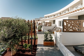 A modern hotel courtyard with a pathway, potted plants, and outdoor seating. - 001 HIGOS BEACH BOUTIQUE Singular Hotel Residence (Pajara)