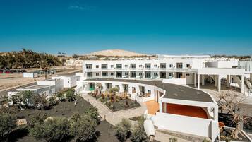 A modern hotel with a courtyard, white exterior, and a view of the surrounding landscape.