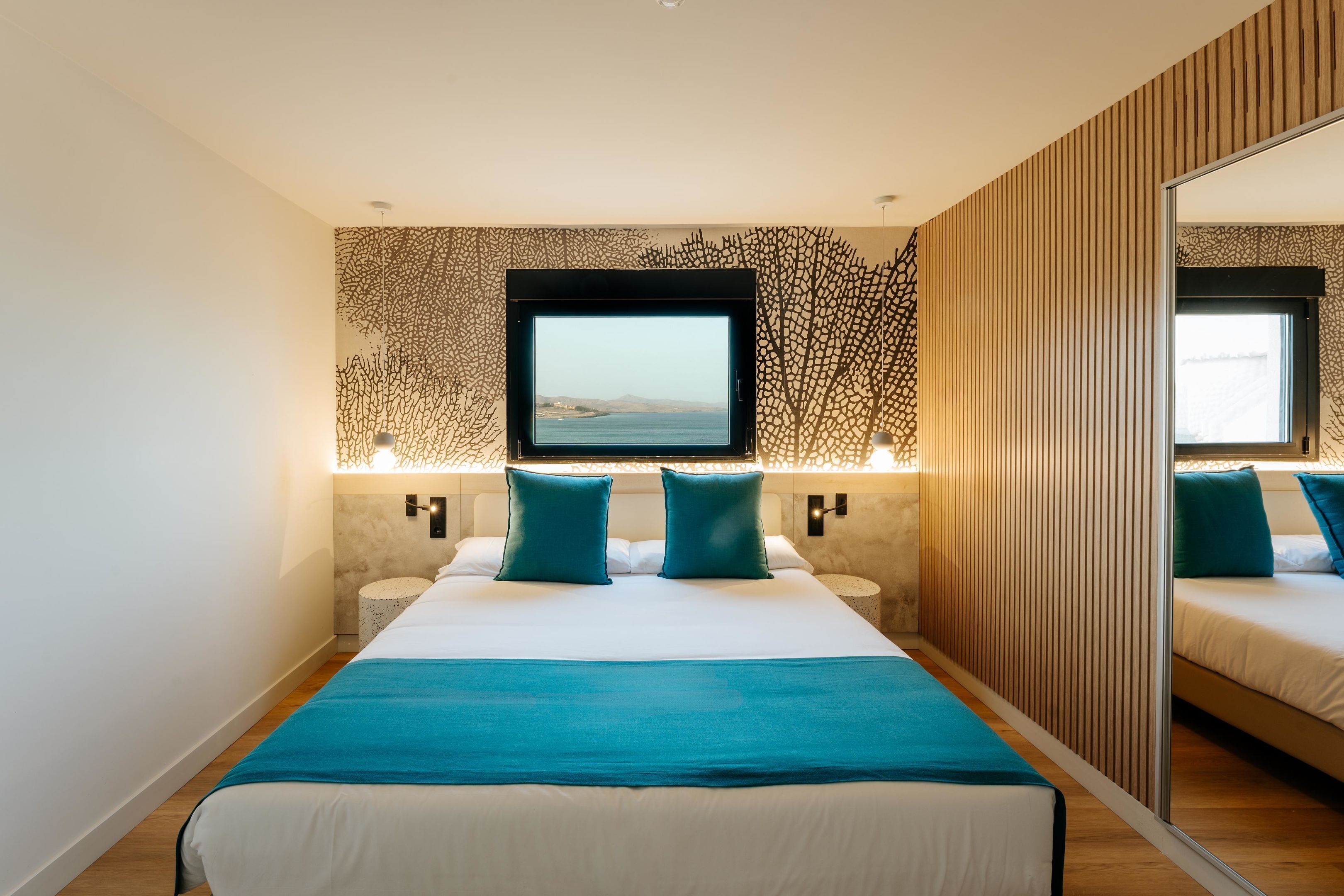 A modern hotel room with a large bed, a TV, and a mirror.