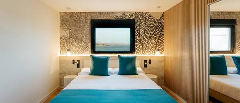 A modern hotel room with a large bed, a TV, and a mirror.
