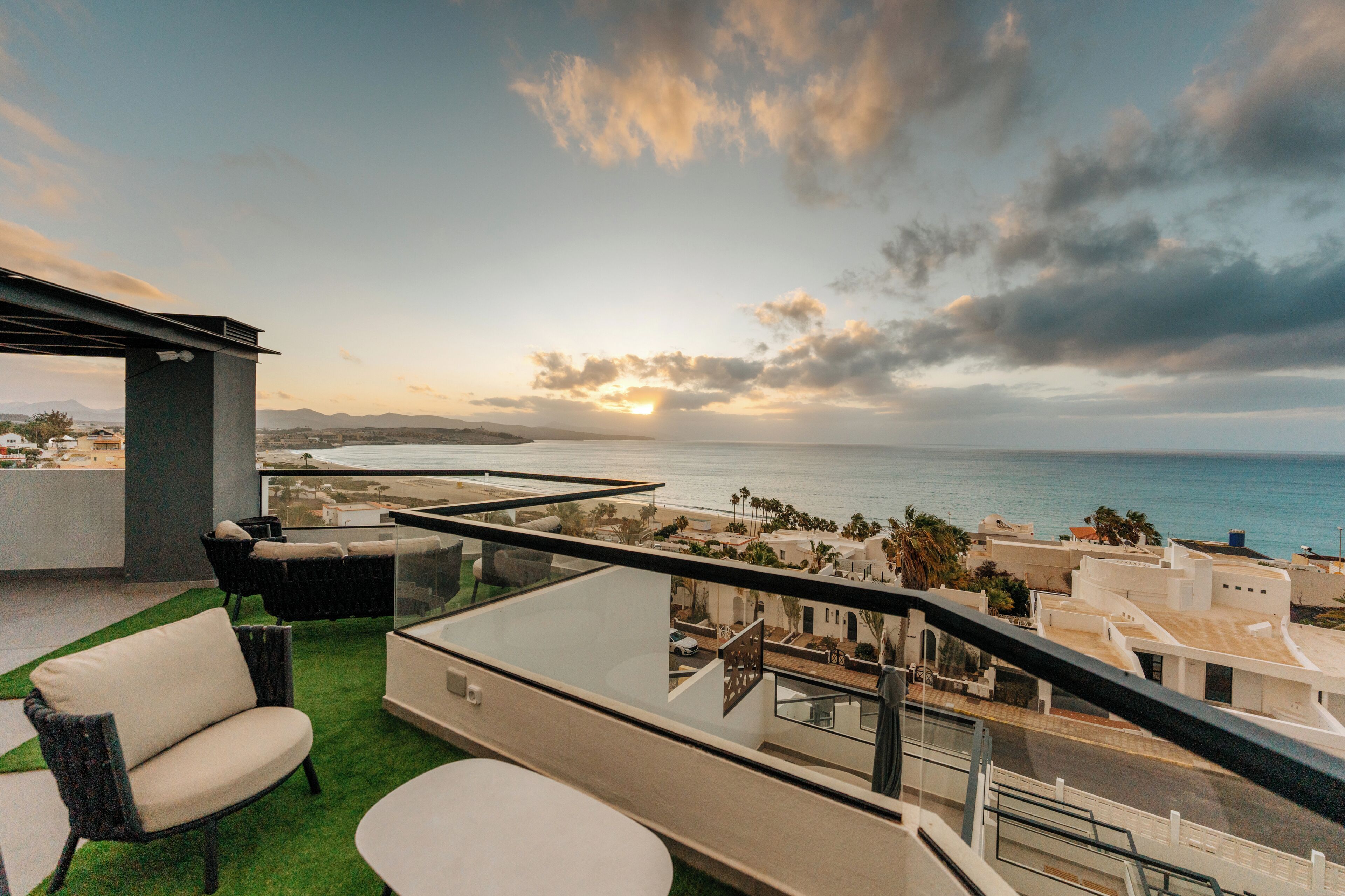 A terrace with outdoor seating and a view of the sea and distant mountains.
