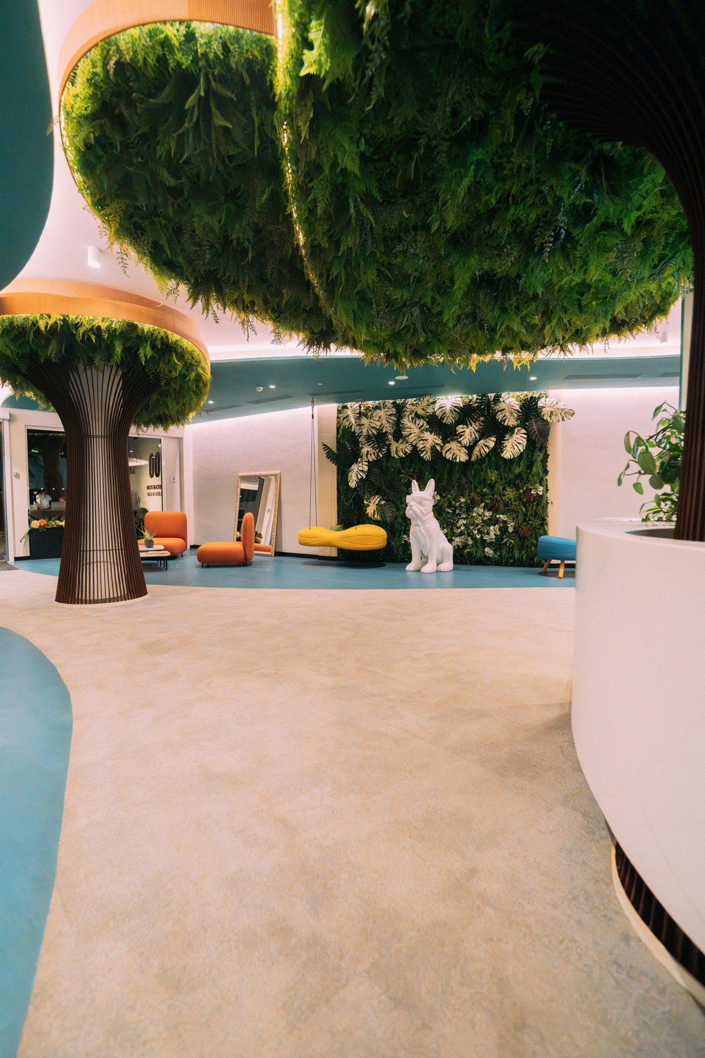 A modern interior with a central tree-like structure, seating areas, and a decorative wall.