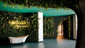 Un intérieur moderne avec un mur vert, une baignoire blanche et un panneau néon sur lequel on peut lire : « BIENVENIDOS Amigos !! ».