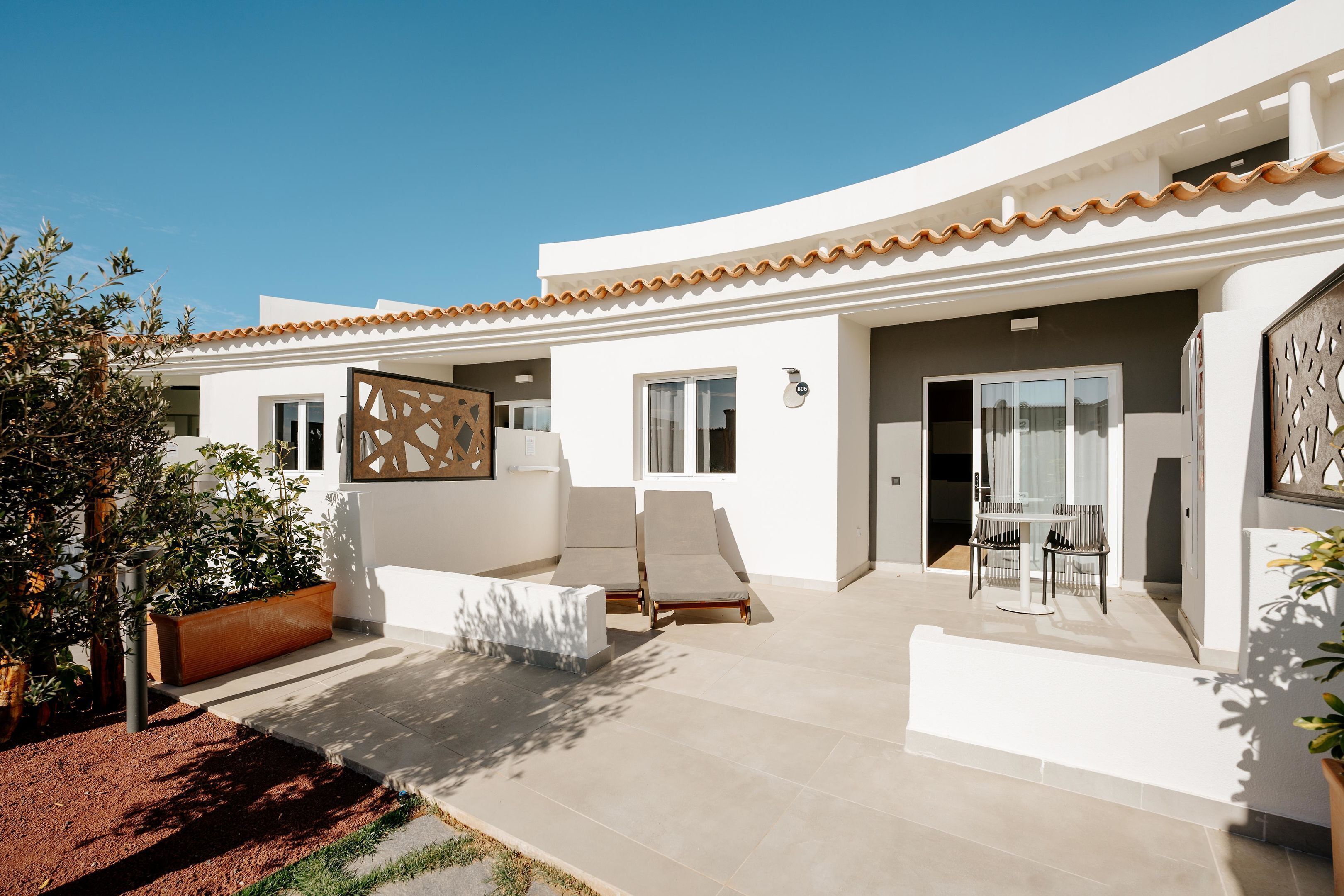 A modern house with a patio area, a built-in bench, and a table with chairs.