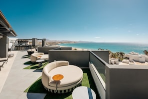 A rooftop terrace with a pool, outdoor seating, and a view of the ocean.