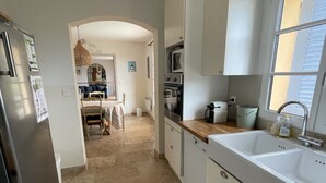 Une cuisine avec des meubles blancs, un évier à deux bacs, un four à micro-ondes et une cuisinière.