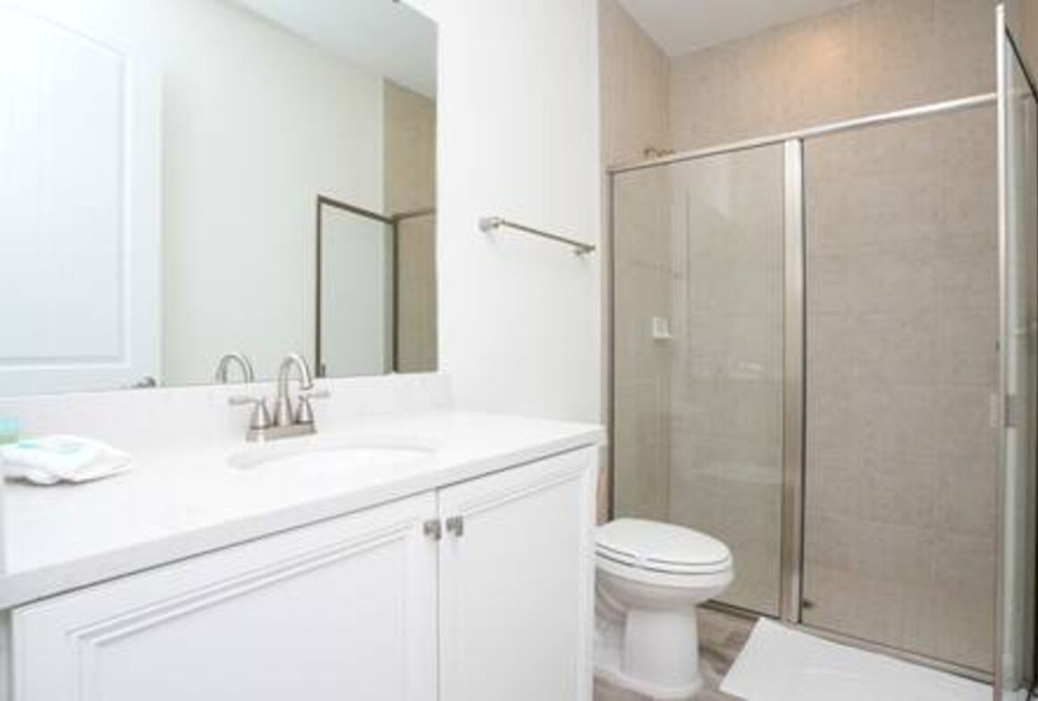 A modern bathroom with a white sink, mirror, and toilet.