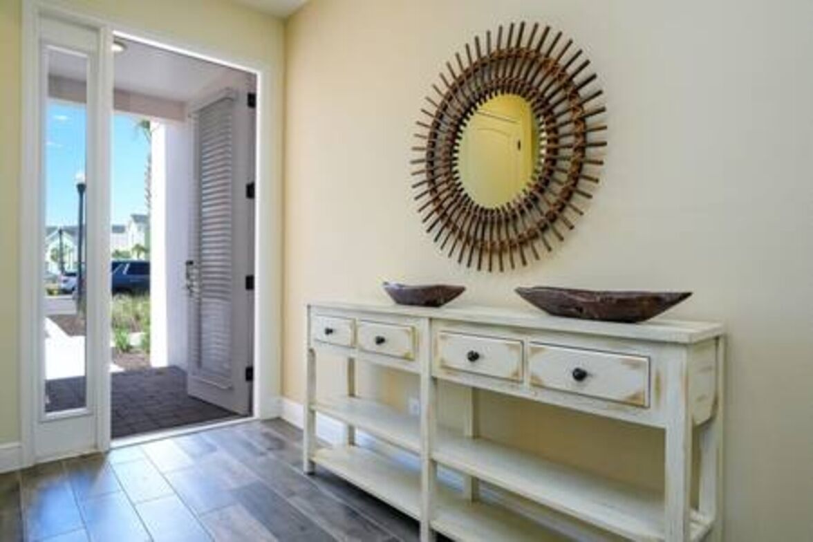 A hallway with a white console table, a decorative mirror, and a door leading outside.