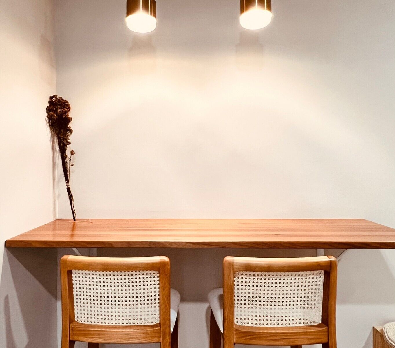 A wooden table with two wicker chairs.