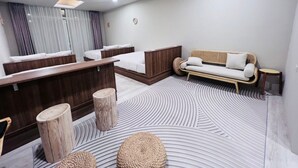 A modern hotel room with a large bed, a sofa, a desk, and a patterned floor. - RiverChill Inn (Tainan)