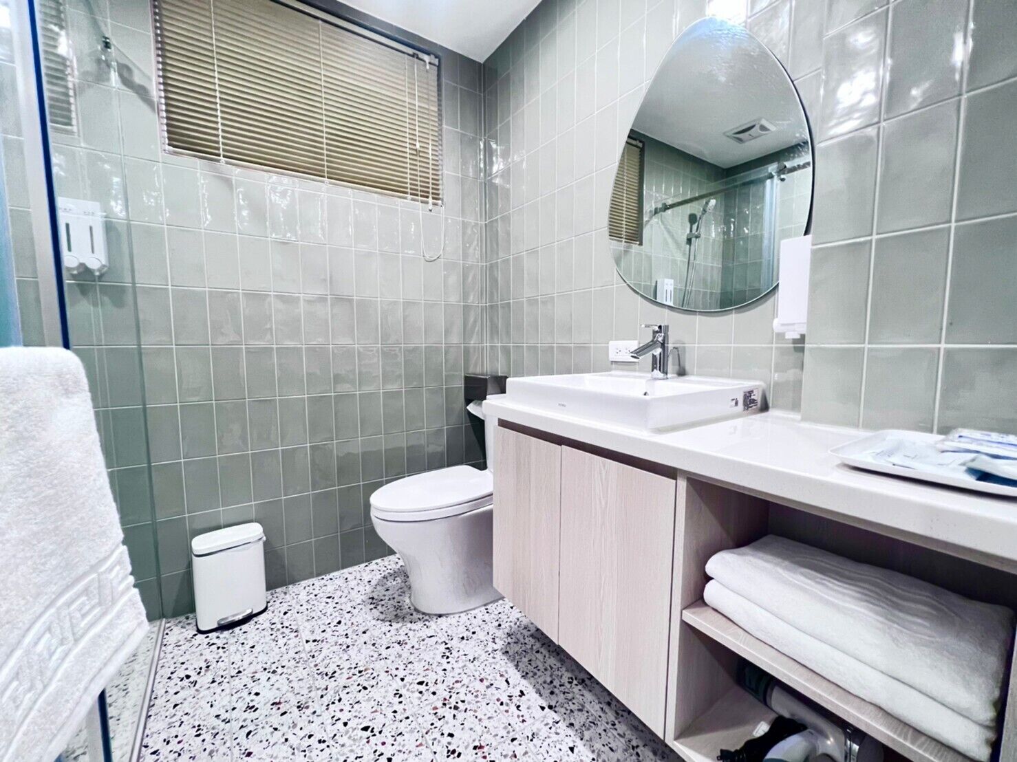 Une salle de bain avec un lavabo blanc, des toilettes et un miroir au-dessus du lavabo.