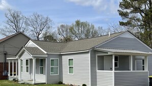 Eenlaags huis met een veranda, een garage en een kleine aangebouwde schuur.