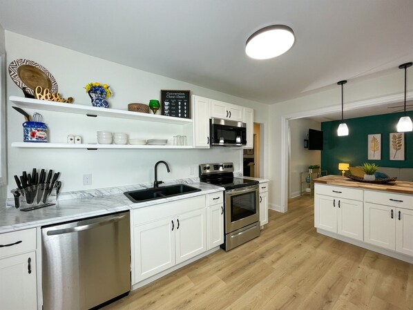 A modern kitchen with white cabinetry, stainless steel appliances, and a wooden countertop. - NEW w/ King Bed Near Tennis Center & Berry College (Rome)