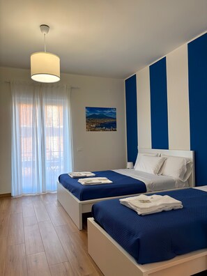 A hotel room with two beds, a large window with sheer curtains, a painting of a landscape, and a blue and white striped wall. - Pompei Art (Scafati)