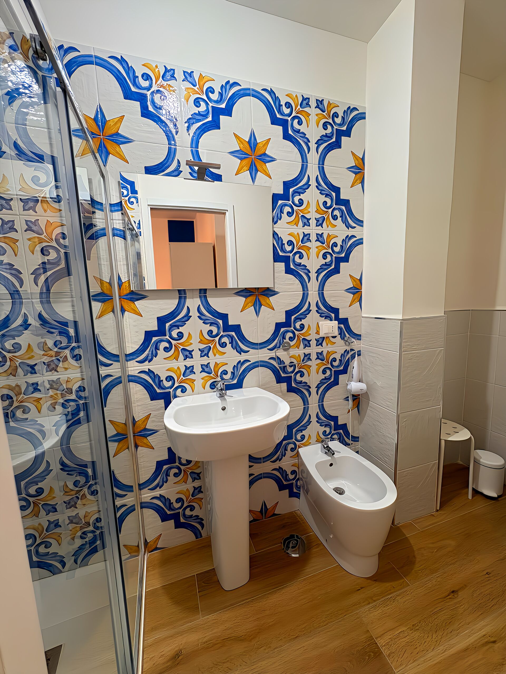 A bathroom with a sink, bidet, and a mirror.