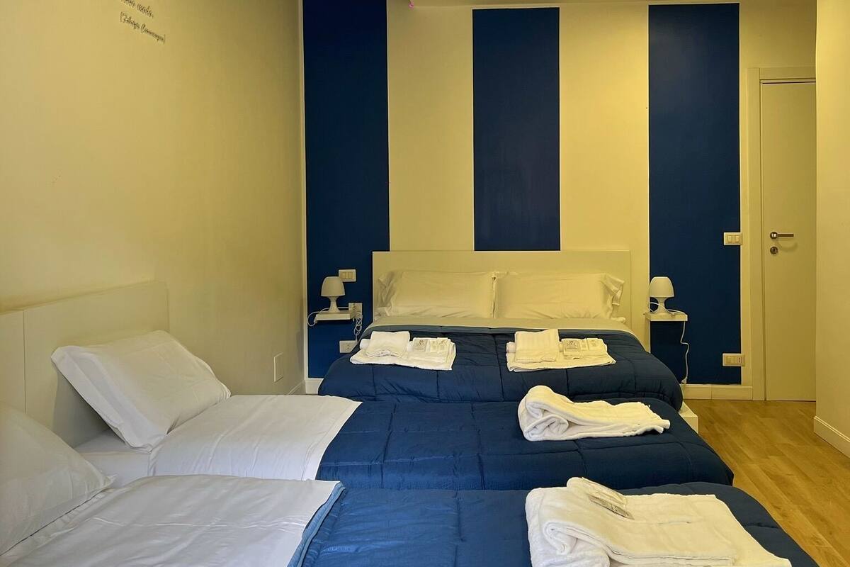 A hotel room with two beds, each with white and blue bedding, and towels neatly folded on the beds.