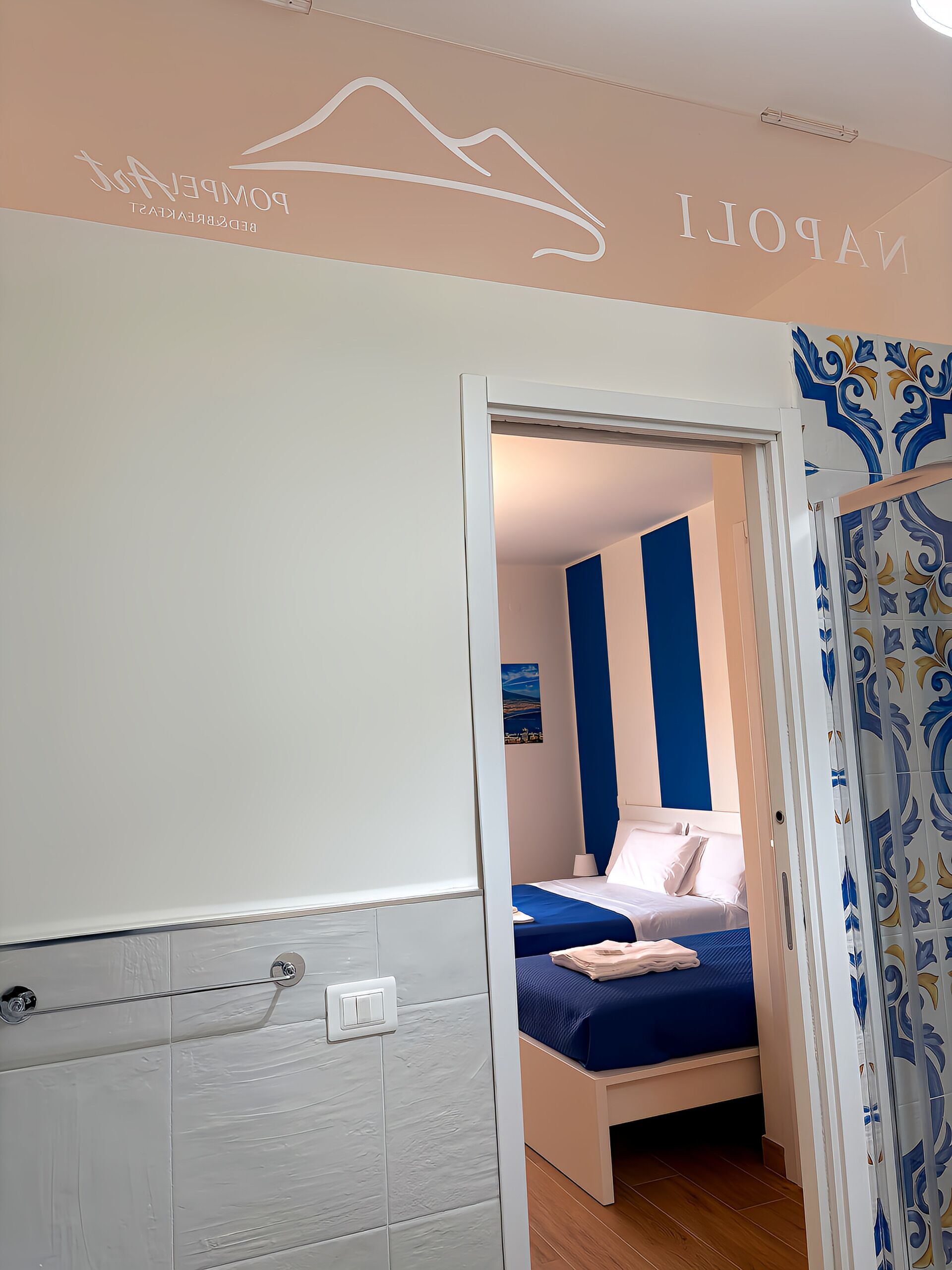 Une chambre d’hôtel avec un lit, une salle de bain dotée d’un porte-serviettes et une porte ornée d’un motif décoratif.