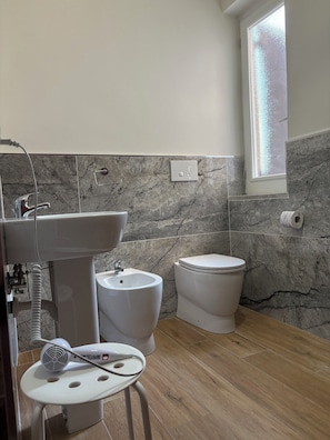 A bathroom with a sink, toilet, and a small stool with a hairdryer. - Pompei Art (Scafati)