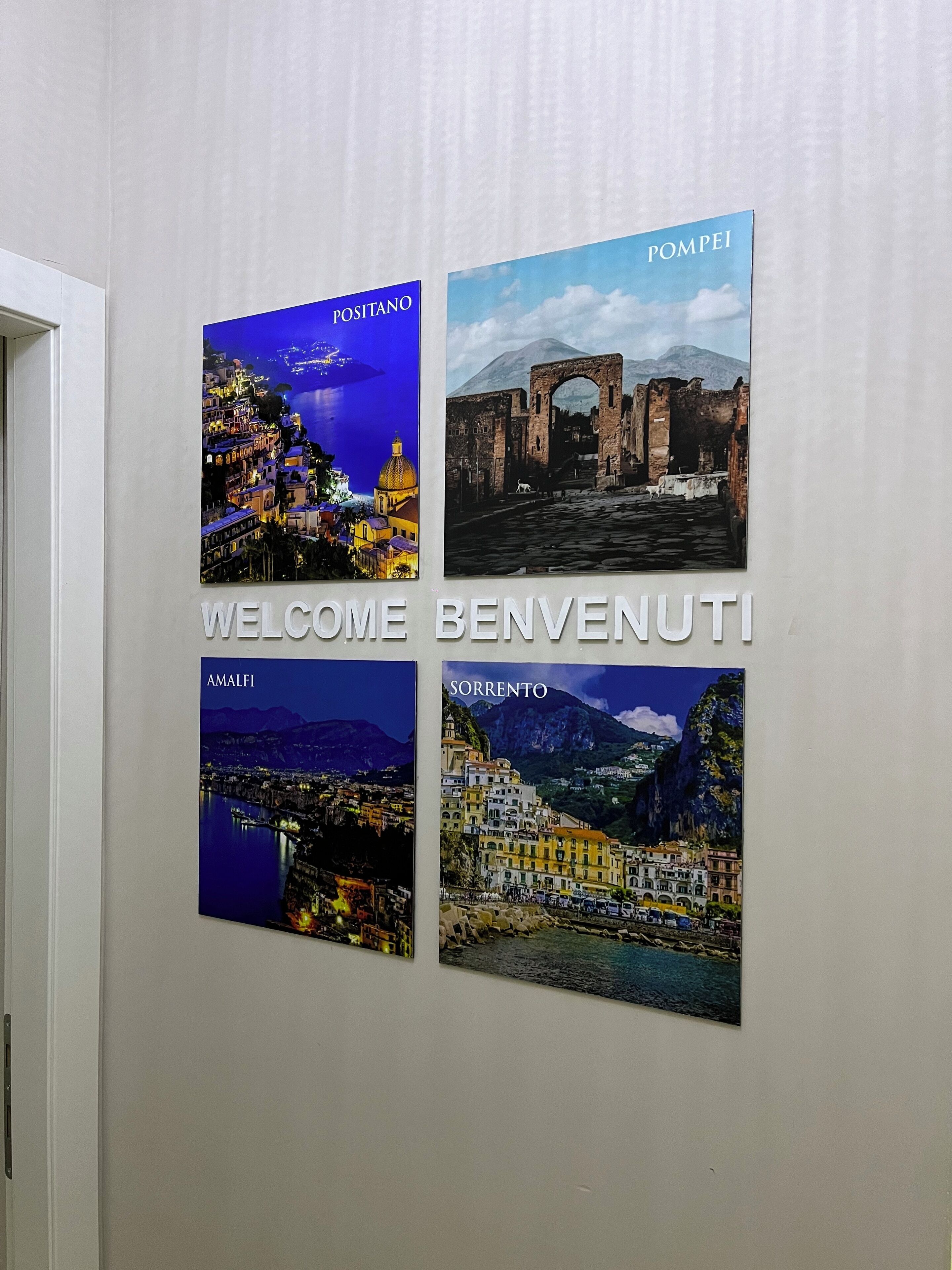 Eine Wand mit vier gerahmten Bildern verschiedener Orte, jedes mit einem Namen beschriftet.
