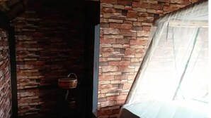 Ein Zimmer mit Backsteinwand, einem Holzeimer und einem Bett mit weißer Bettdecke.