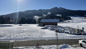 Eine verschneite Landschaft mit einem Gebäude, einer Straße und Bergen im Hintergrund.